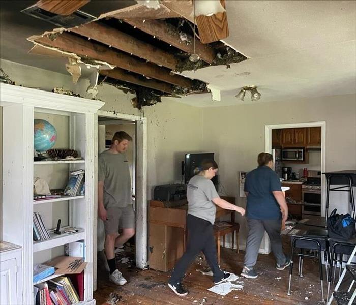 Fire-damaged lining room with 3 people walking through